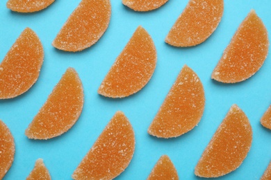 Photo of Delicious orange marmalade candies on light blue background, flat lay
