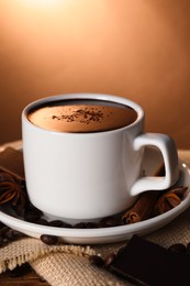 Photo of Cup of delicious hot chocolate, spices and coffee beans on table