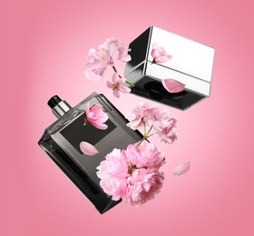 Bottle of perfume and sakura flowers in air on pink background