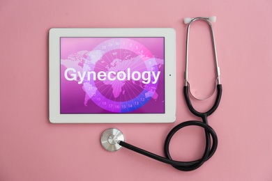 Stethoscope and tablet with word GYNECOLOGY on color background, top view