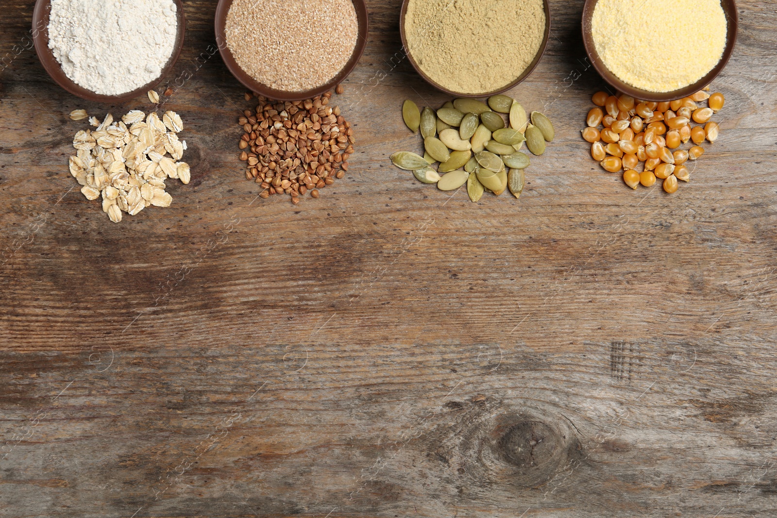 Photo of Flat lay composition with different types of flour and seeds on wooden background. Space for text