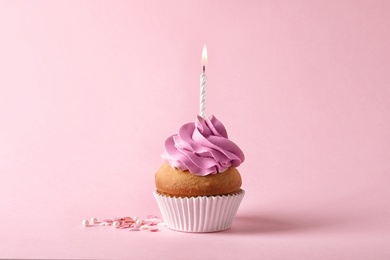 Photo of Delicious birthday cupcake with candle on color background