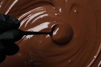 Person making tasty milk chocolate paste, top view