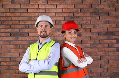 Photo of Industrial engineers in uniforms on brick wall background. Safety equipment