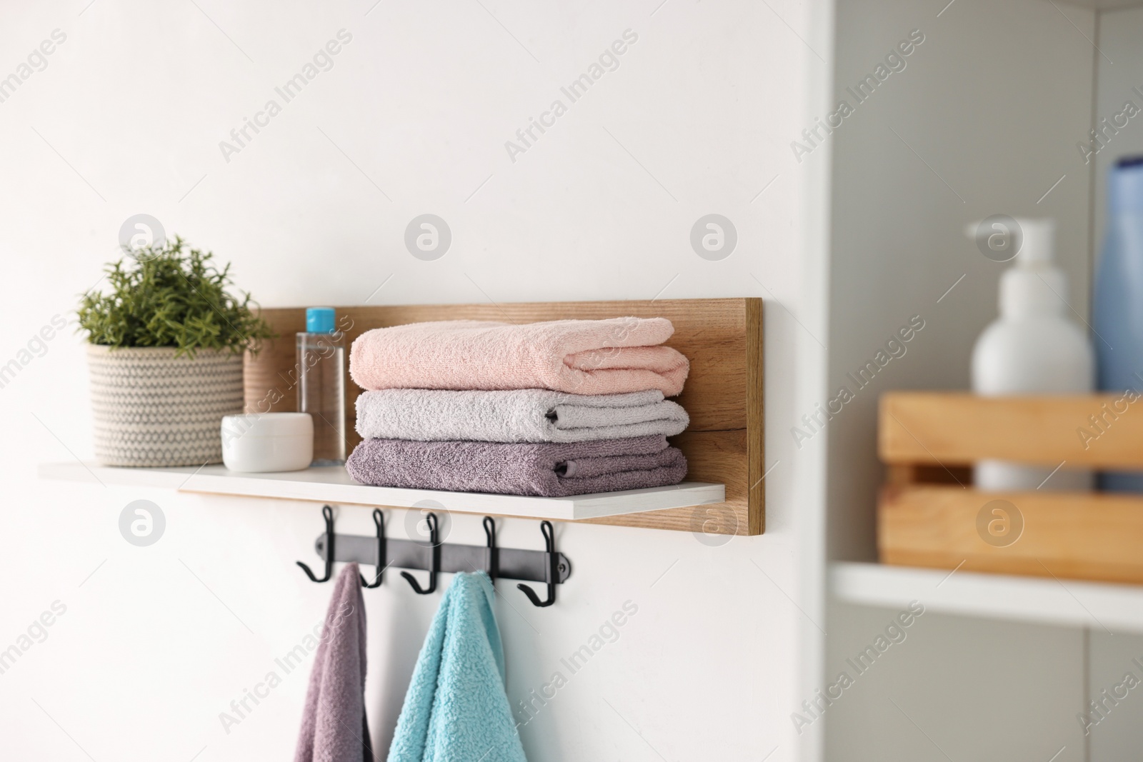 Photo of Clean towels, houseplant and toiletries on shelf indoors