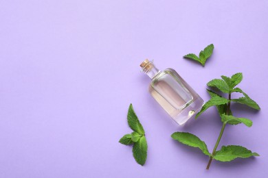 Photo of Bottle of essential oil and mint on violet background, flat lay. Space for text