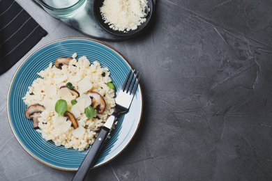 Photo of Delicious risotto with cheese and mushrooms on dark grey table, flat lay. Space for text