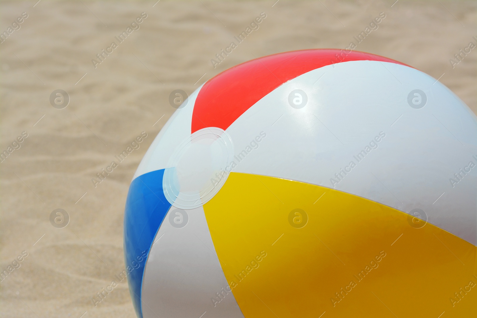 Photo of Colorful beach ball on sand, closeup view