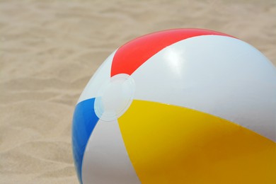 Colorful beach ball on sand, closeup view