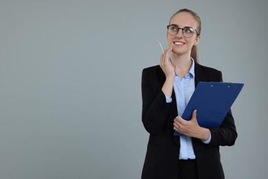 Photo of Happy young secretary with clipboard and pen on grey background, space for text