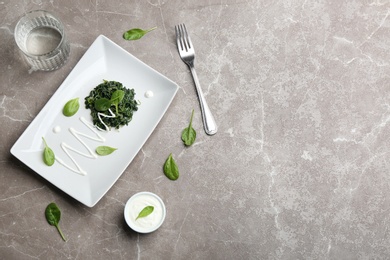 Photo of Flat lay composition with cooked spinach on grey marble table. Healthy food