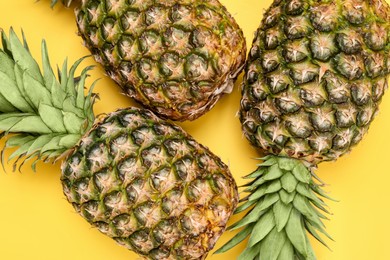 Photo of Whole ripe pineapples on yellow background, flat lay