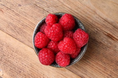 Photo of Tasty ripe raspberries in bowl on wooden table, top view