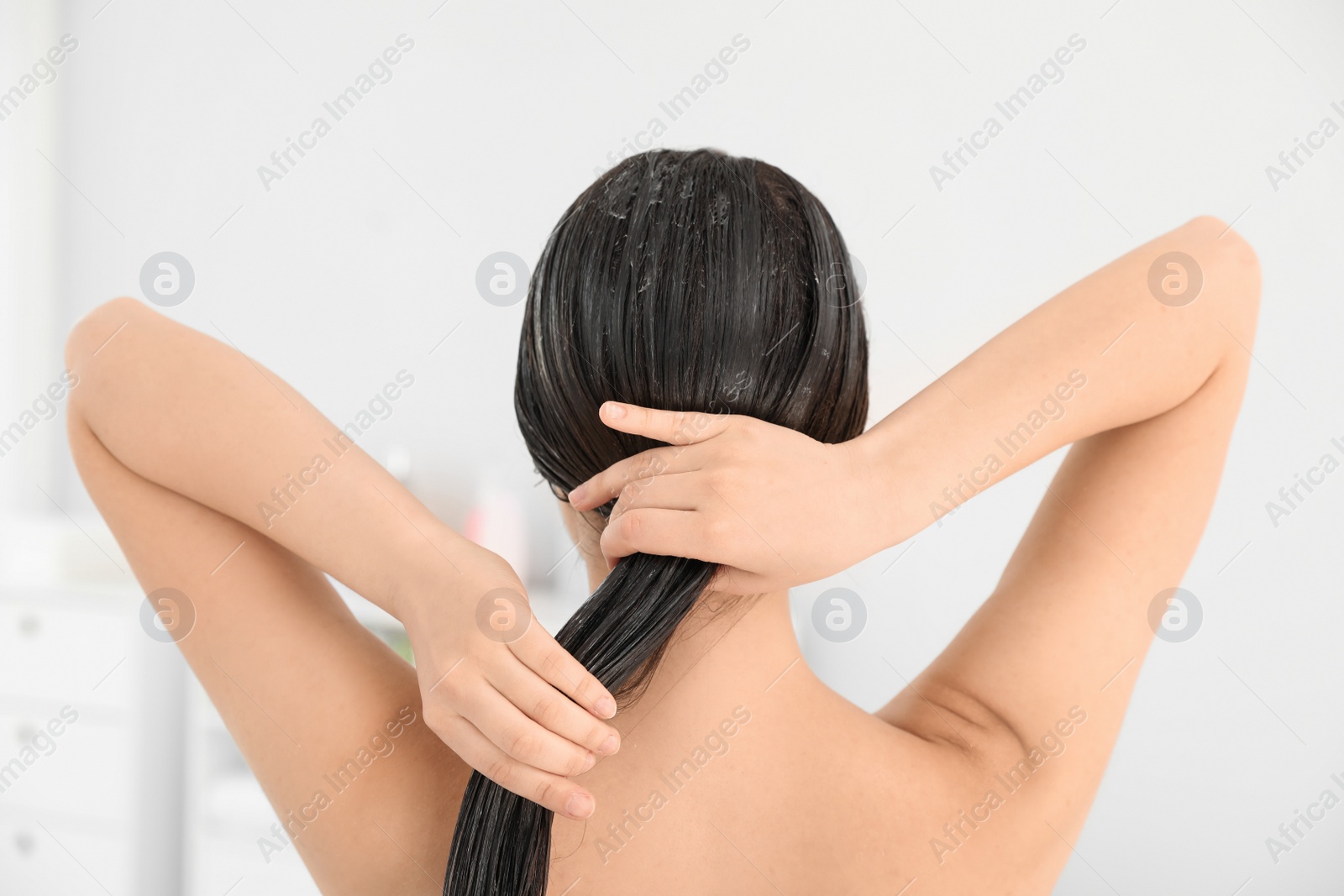 Photo of Woman applying hair conditioner in light bathroom