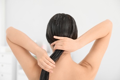 Woman applying hair conditioner in light bathroom