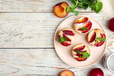 Delicious cupcakes with plums on white wooden table, flat lay. Space for text