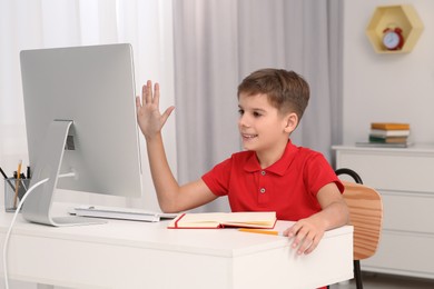 Photo of Boy using computer at desk in room. Home workplace
