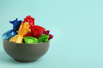 Candies in colorful wrappers on light blue background. Space for text