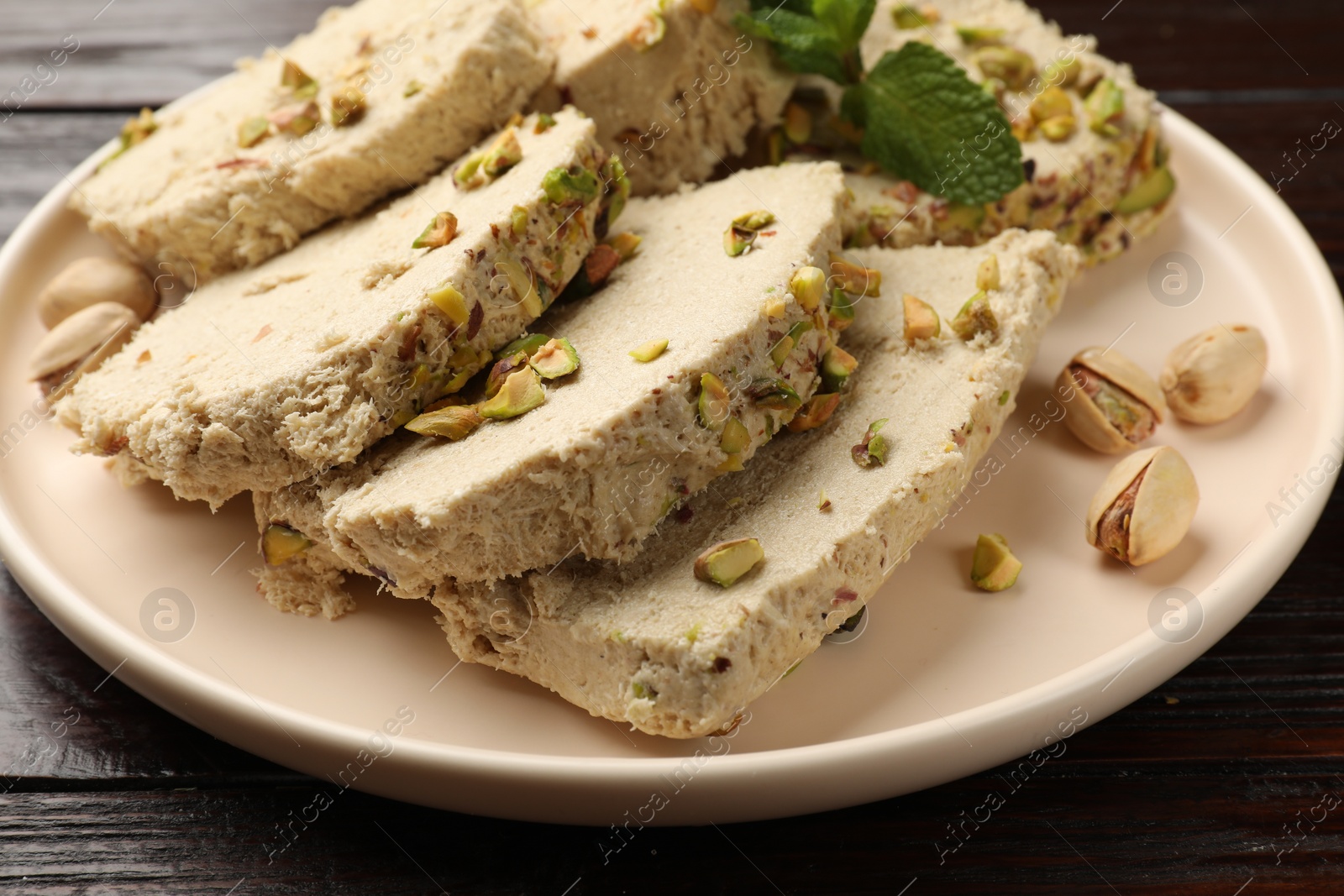 Photo of Pieces of tasty halva with pistachios on table, closeup