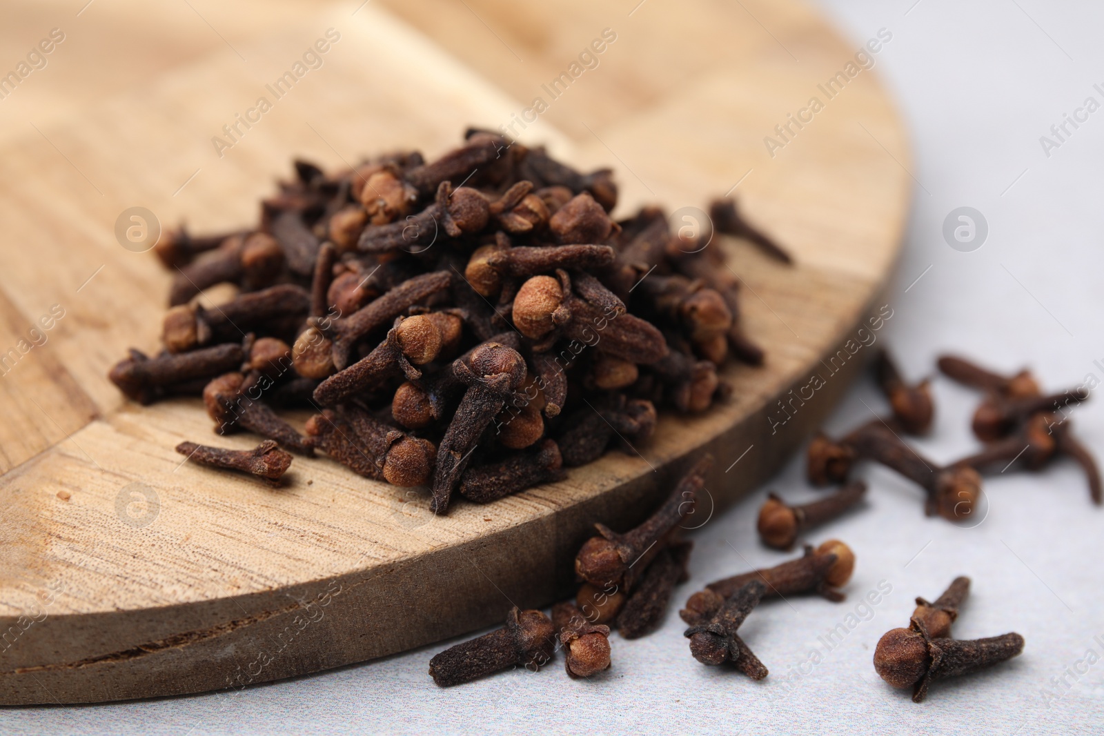 Photo of Pile of aromatic cloves on light table, closeup