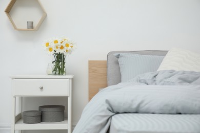 Bouquet of beautiful daisy flowers on nightstand in bedroom