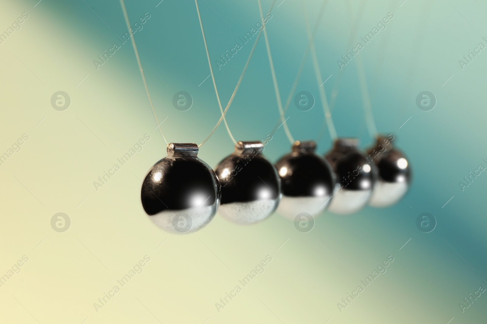 Photo of Newton's cradle on color background, closeup. Physics law of energy conservation