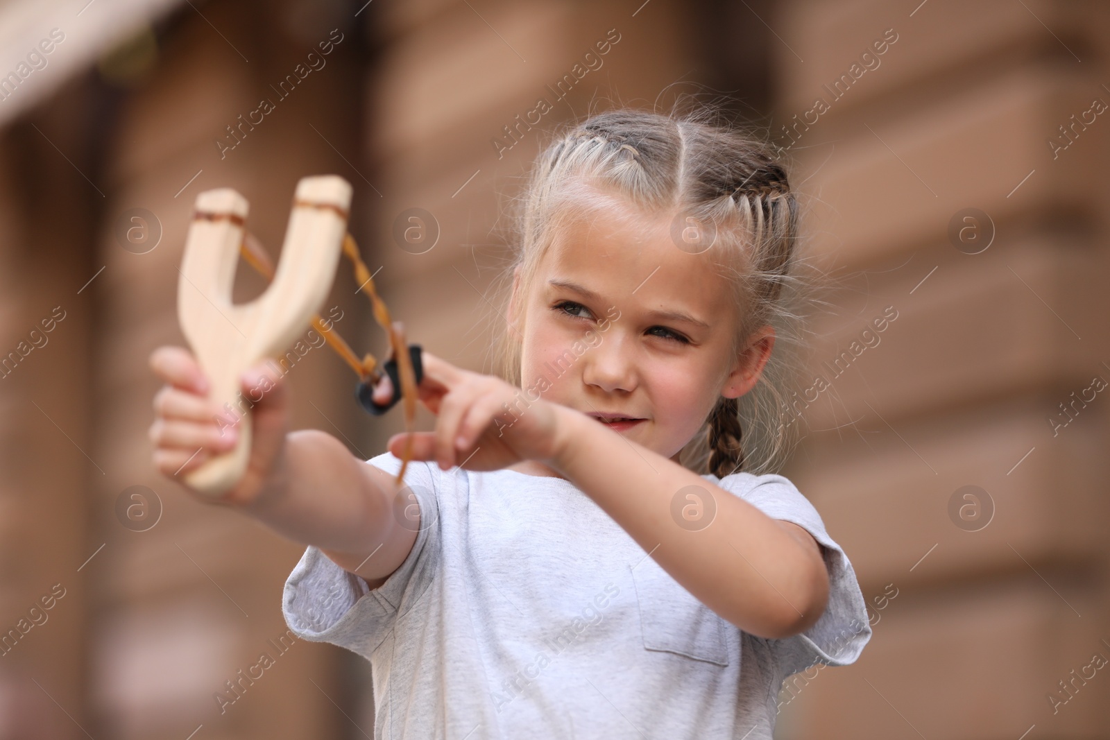 Photo of Little girl playing with slingshot on city street