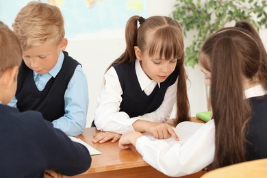 Photo of Little children in classroom. Stylish school uniform