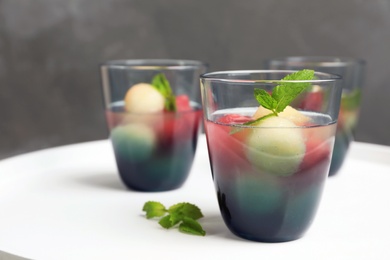 Photo of Glasses with tasty melon and watermelon ball drink on light table against color wall