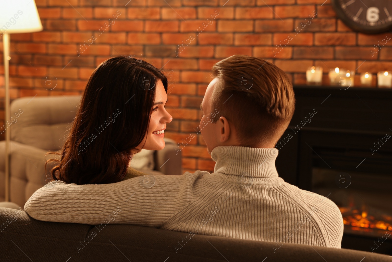 Photo of Lovely couple spending time together near fireplace at home