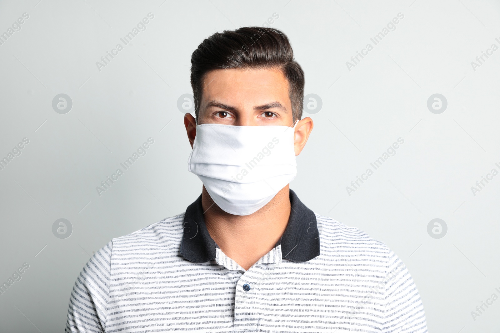 Photo of Man in protective face mask on light grey background