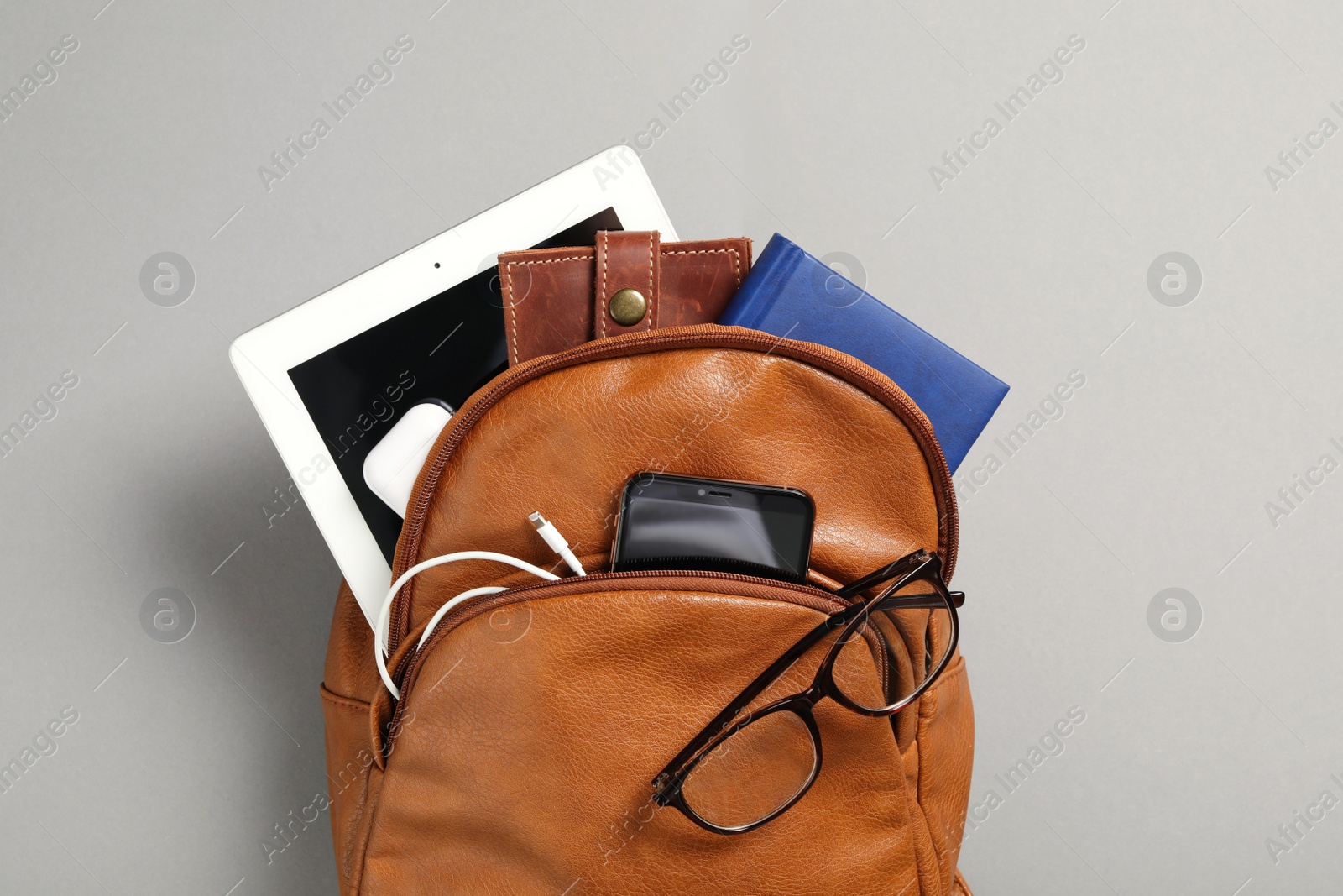 Photo of Stylish urban backpack with different items on grey background, top view