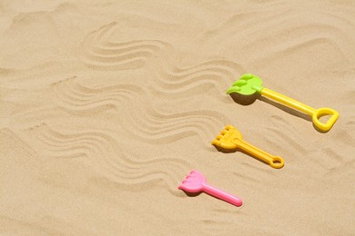 Plastic rakes on sand, space for text. Beach toys