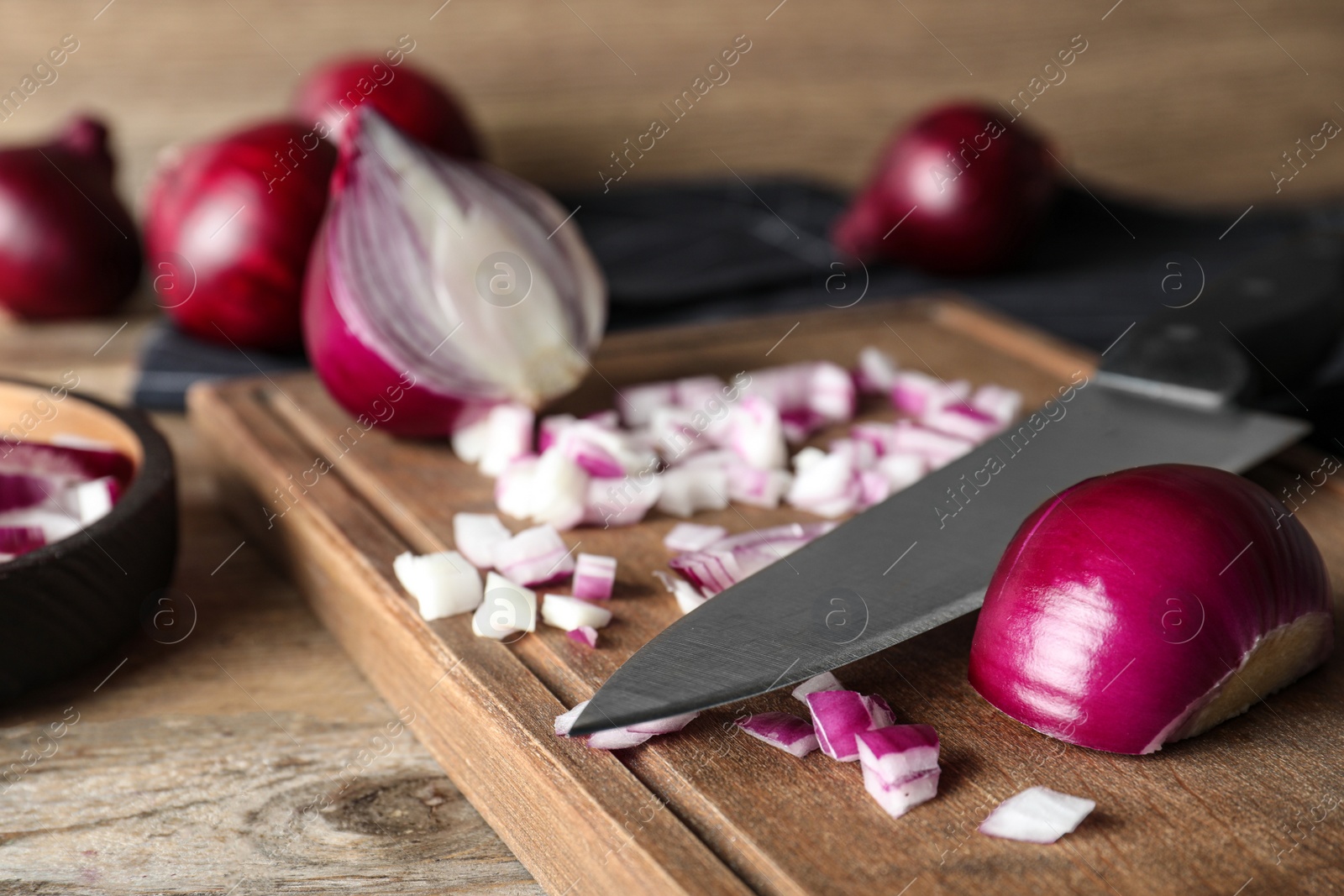 Photo of Board with cut red onion and knife on wooden table