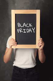 Woman holding blackboard with text BLACK FRIDAY on dark background