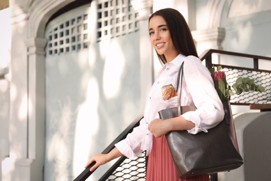 Photo of Young woman with leather shopper bag outdoors