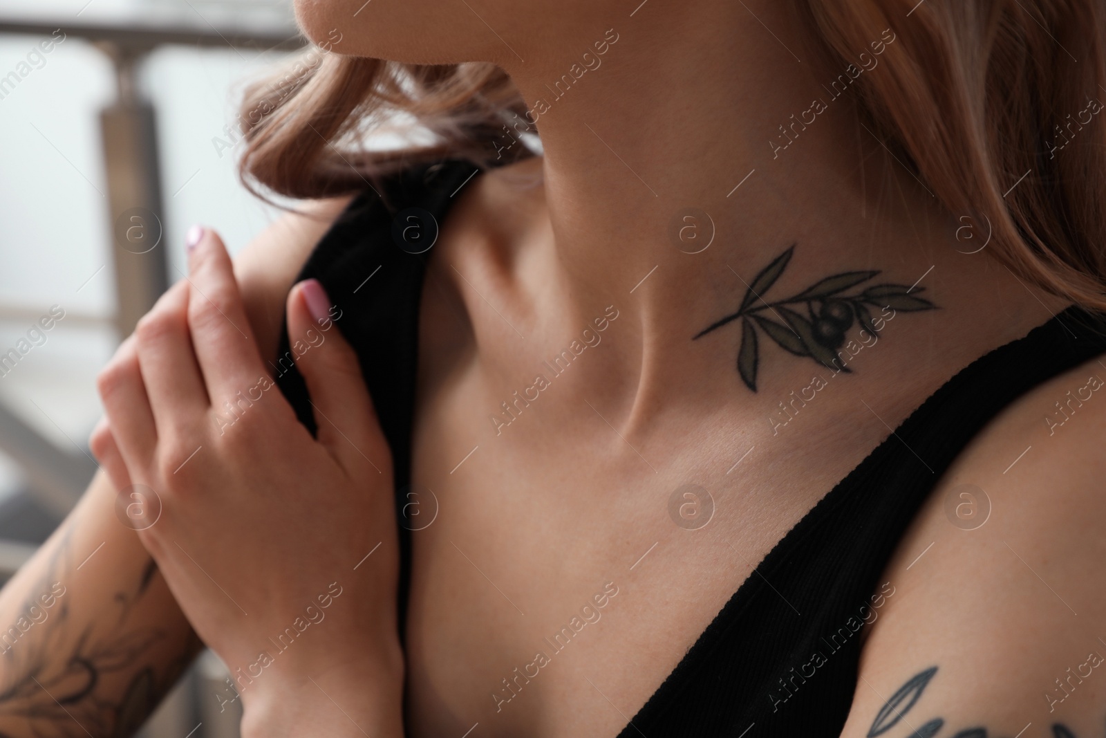 Photo of Beautiful woman with tattoos on body indoors, closeup