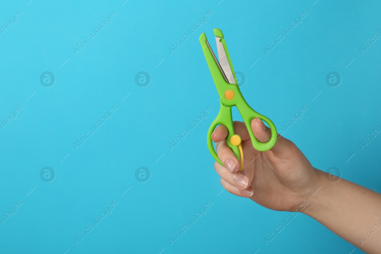 Photo of Woman holding small scissors on turquoise background, closeup. Space for text