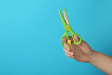 Photo of Woman holding small scissors on turquoise background, closeup. Space for text