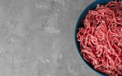 Photo of Bowl of raw minced meat on grey table, top view. Space for text