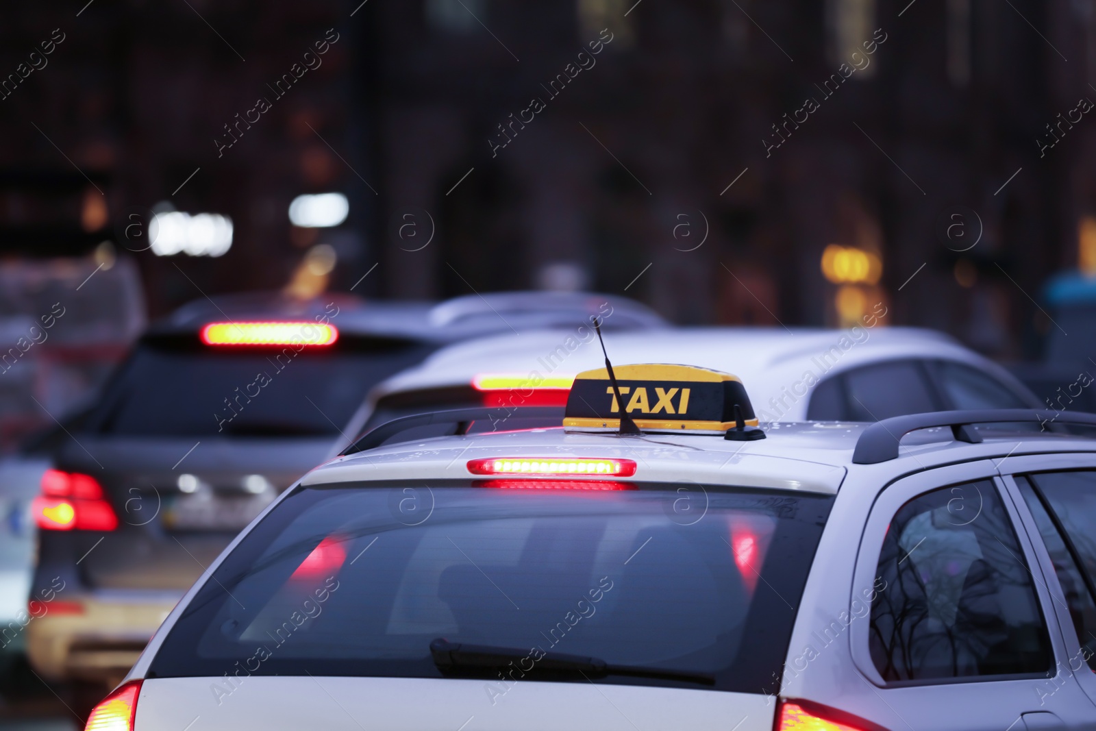 Photo of Taxi car with yellow checkered sign on city street in evening