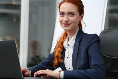 Photo of Happy woman working with laptop in office