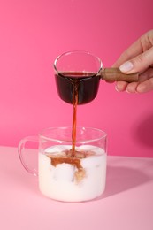 Photo of Woman making iced coffee on pink background, closeup