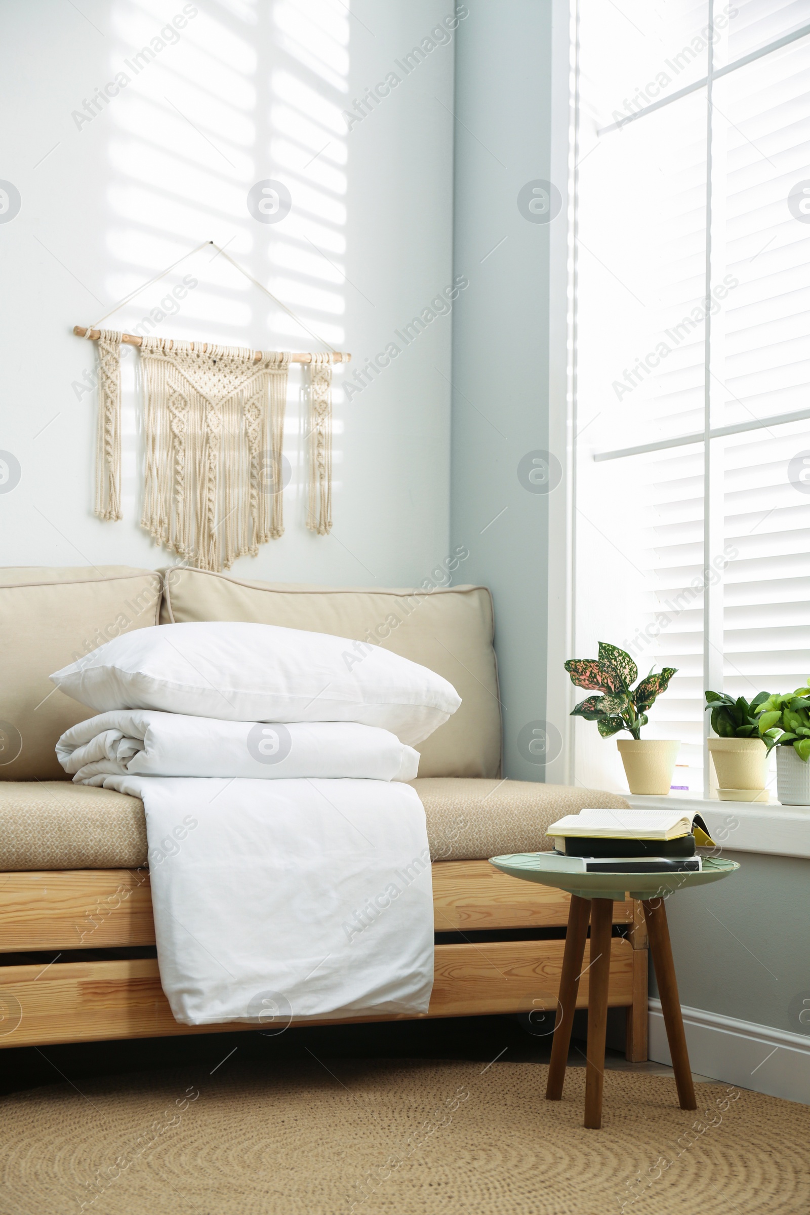 Photo of Comfortable sofa with blanket near window indoors