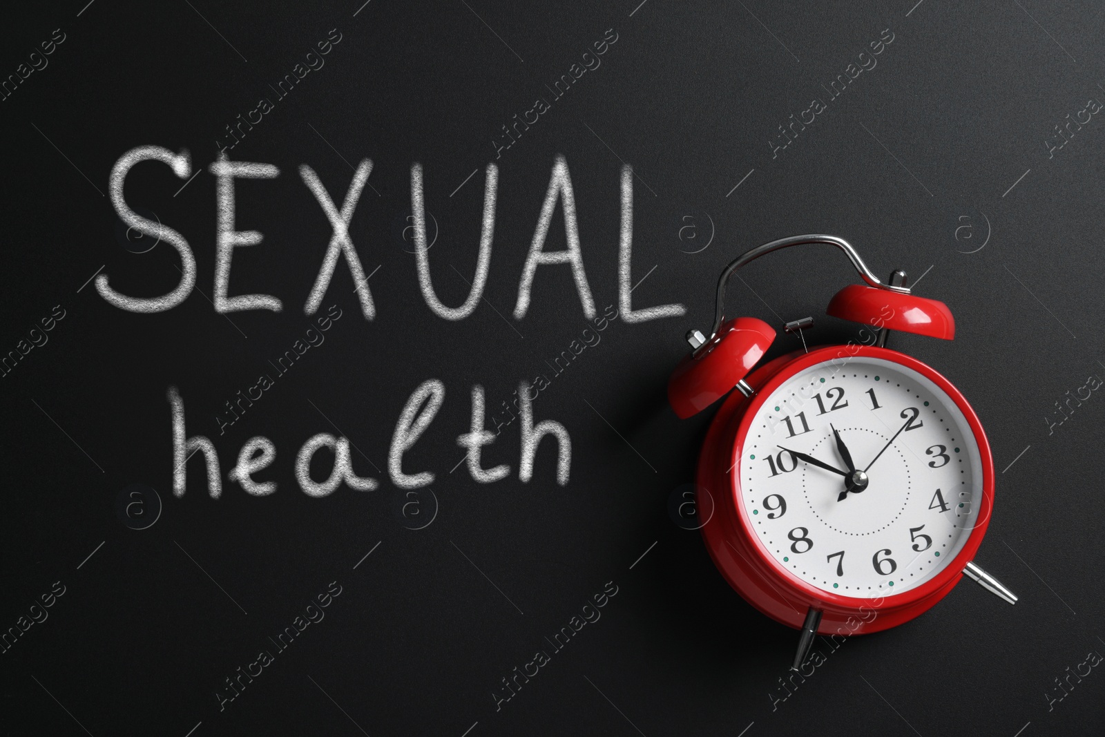 Image of Sex education. Alarm clock and chalked words Sexual Health on blackboard