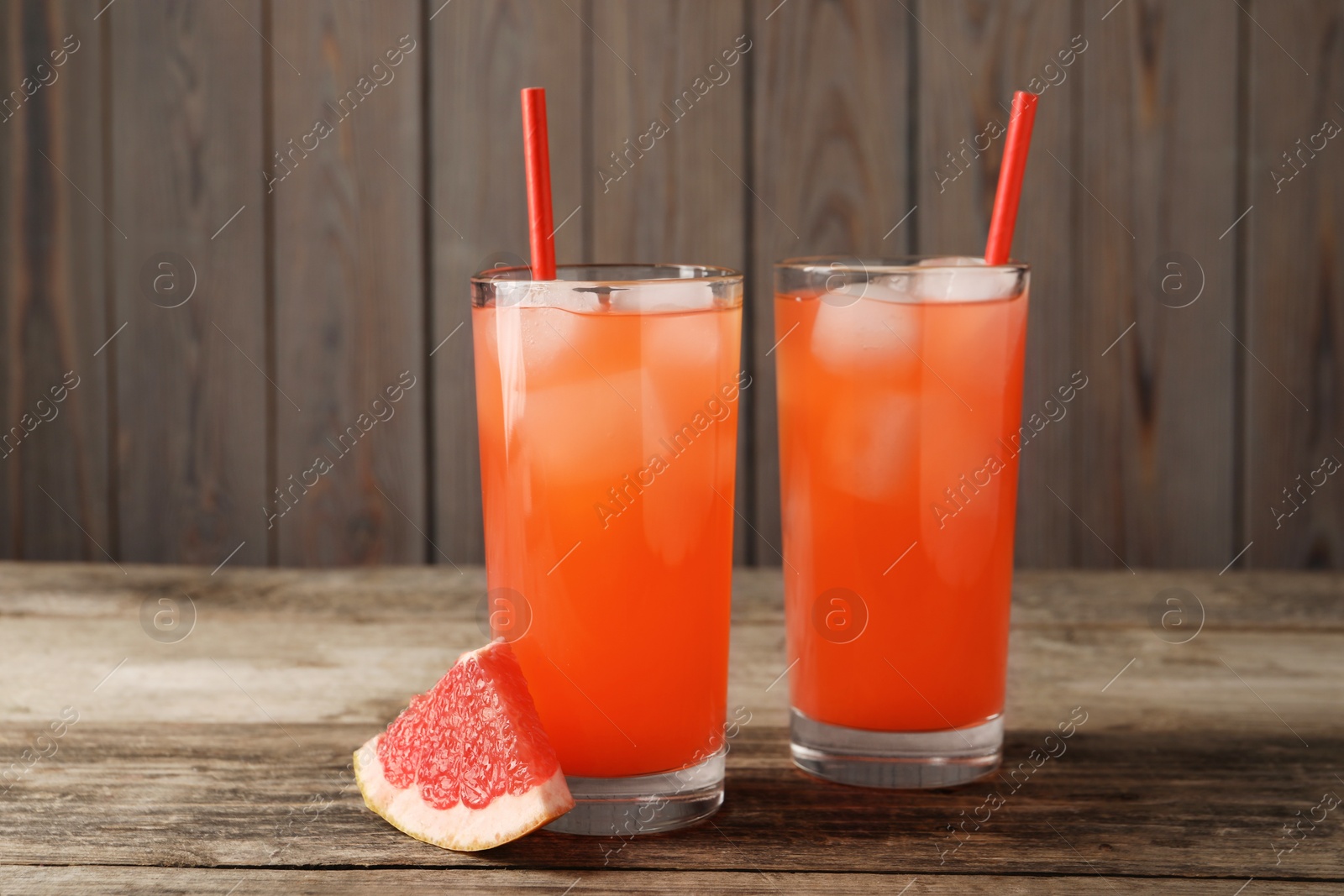 Photo of Tasty freshly made grapefruit juice and fruit on wooden table