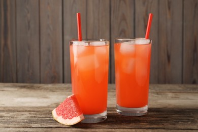 Photo of Tasty freshly made grapefruit juice and fruit on wooden table