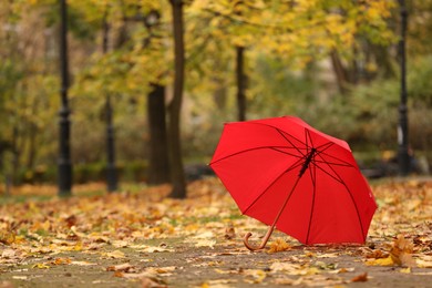 Photo of Open red umbrella in autumn park, space for text