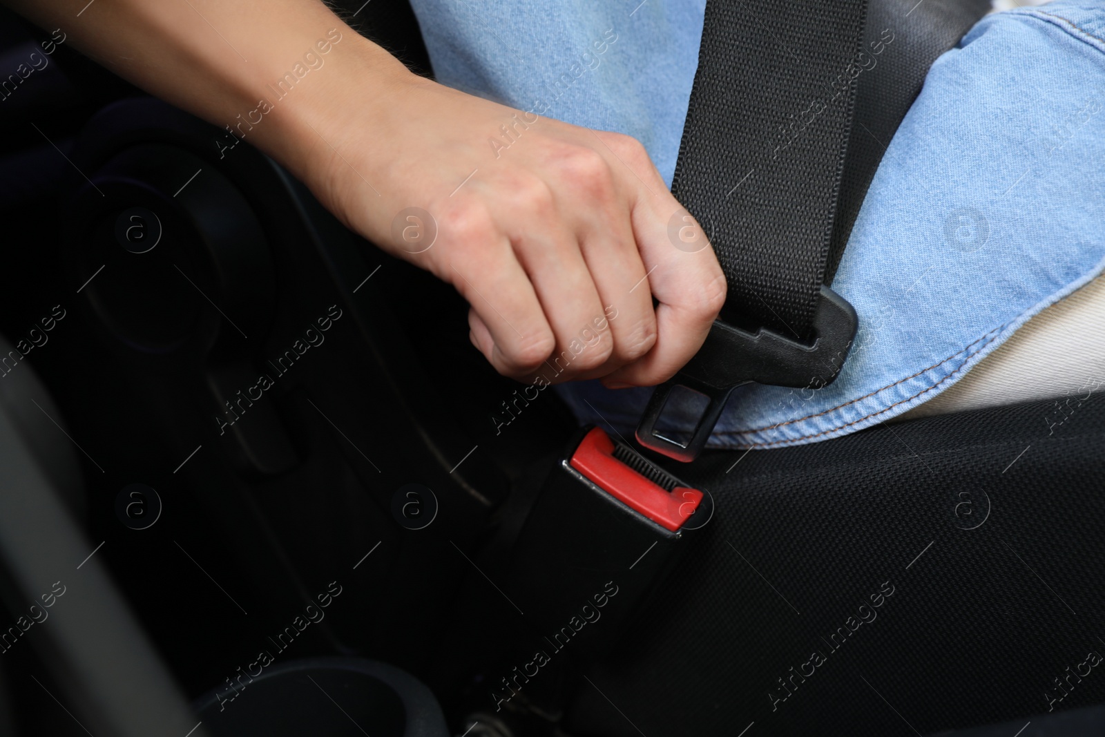Photo of Woman fastening safety belt on driver's seat in car, closeup