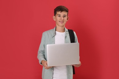 Photo of Teenage student with backpack and laptop on red background